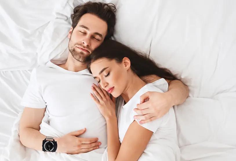 Man sleeping with the Sleep Connection wristband next to his partner